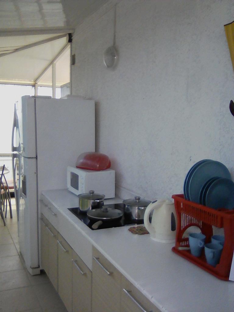 Общая летняя кухня, оборудованная современной бытовой техникой, посудой, столовыми приборами и домашней утварью