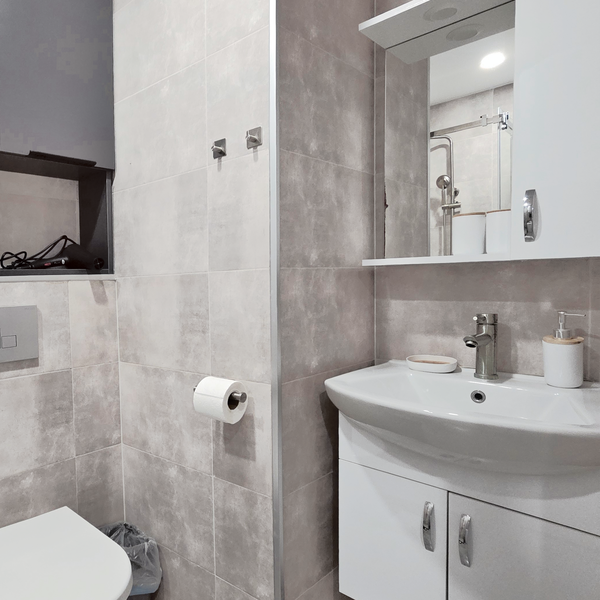 Современный санузел с душевой кабиной, раковиной с зеркалом и удобными шкафчиками для хранения. В распоряжении гостей стиральная машина и фен. Чистое, светлое и функциональное пространство для комфортного проживания.